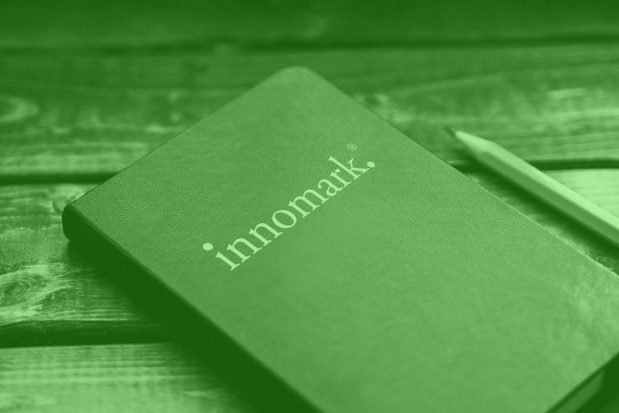 In Gruen getauchtes Bild eines Notizbuches mit der Aufschrift innomark, picture of a notebook immersed in green with the inscription innomark